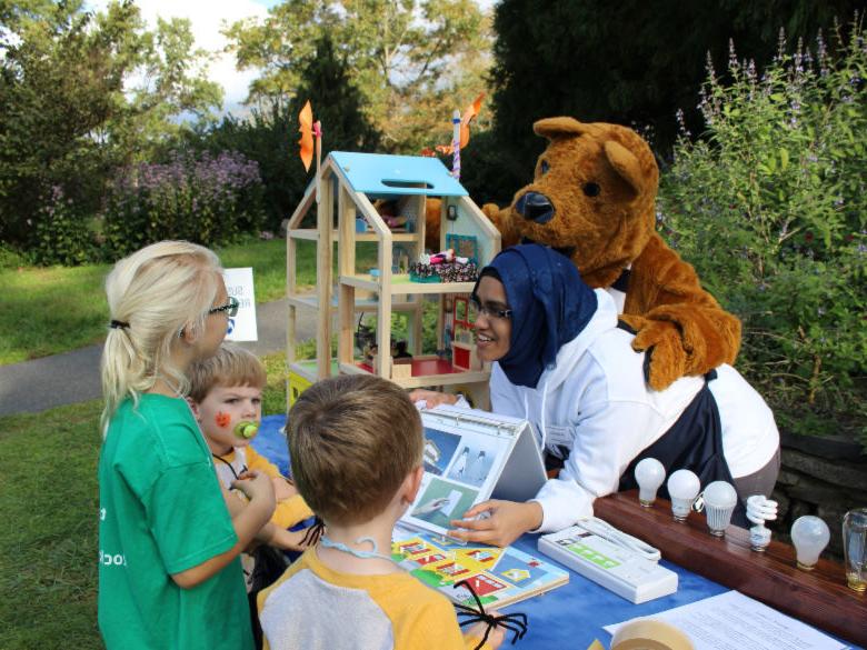 Student and lion mascot helping children.